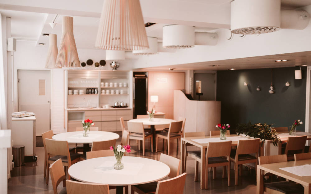 Valoisa ja tunnelmallinen opetusravintola Poukama, jonka pöydillä on runsaasti punaisia ja valkoisia tulppaaneja.